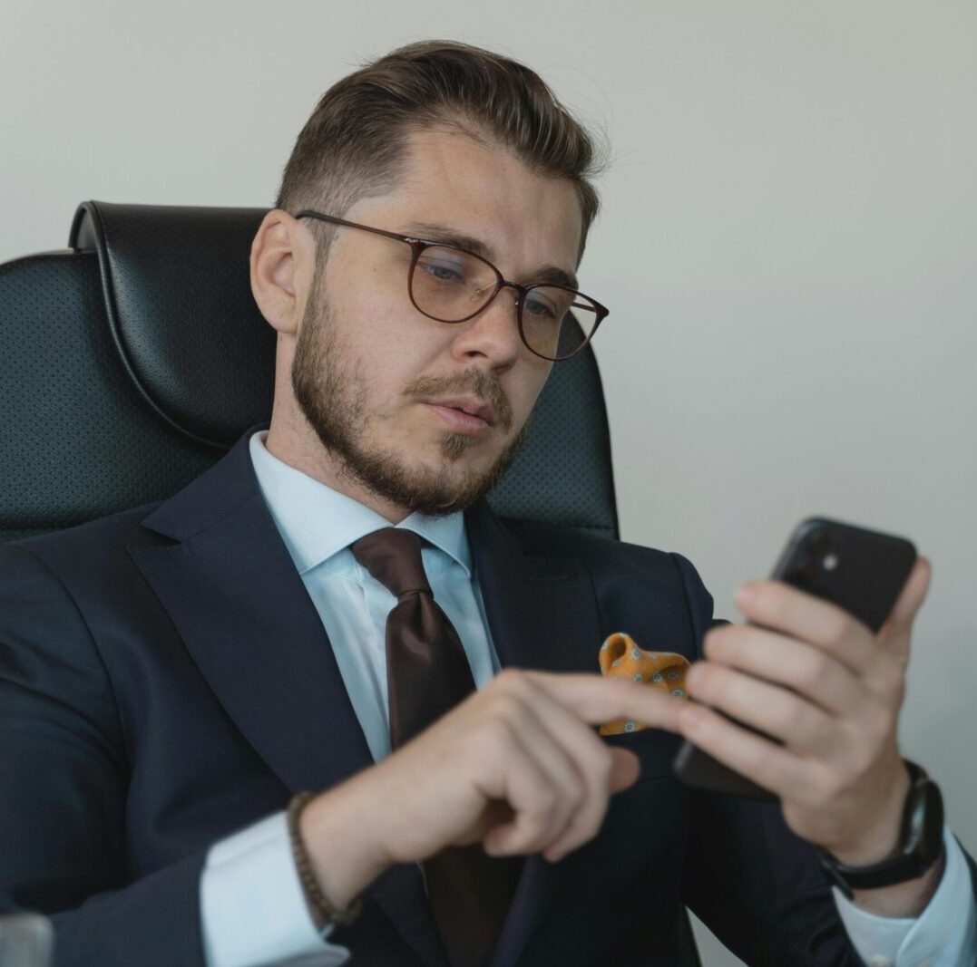 Professional businessman in a formal suit using his smartphone in an office setting.